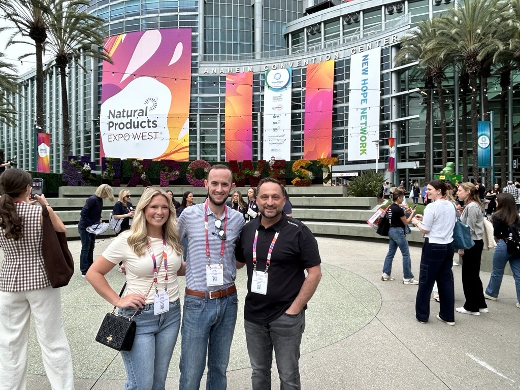 Survey Team Attendees posing outside the Natural Products Expo West entrance at the Anaheim Convention Center.